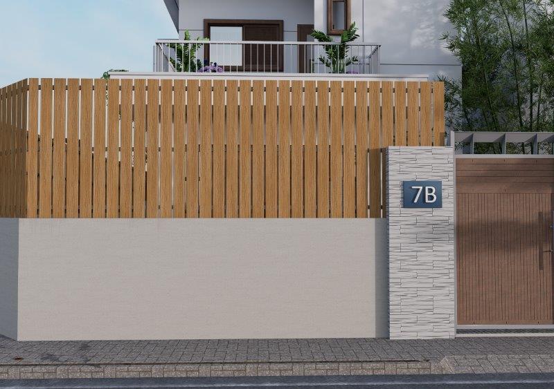 Tall wooden slat fence over a light gray concrete wall, with a blue 7B plaque on a stone column beside a wooden gate; modern home behind.